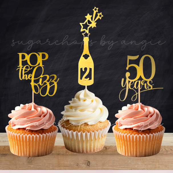 Three cupcakes topped with decorative picks: "Pop the Bubbly," a champagne bottle, and "50 Years."